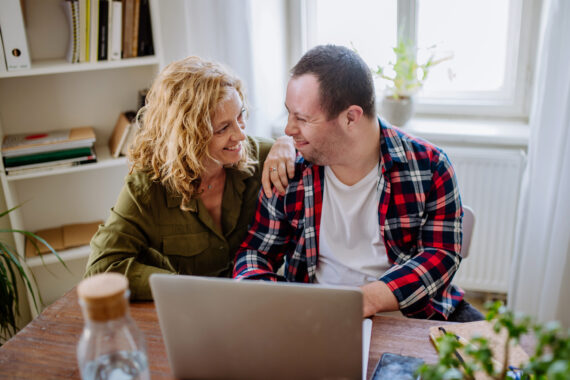Two people sitting at a table with a computer in front of them.