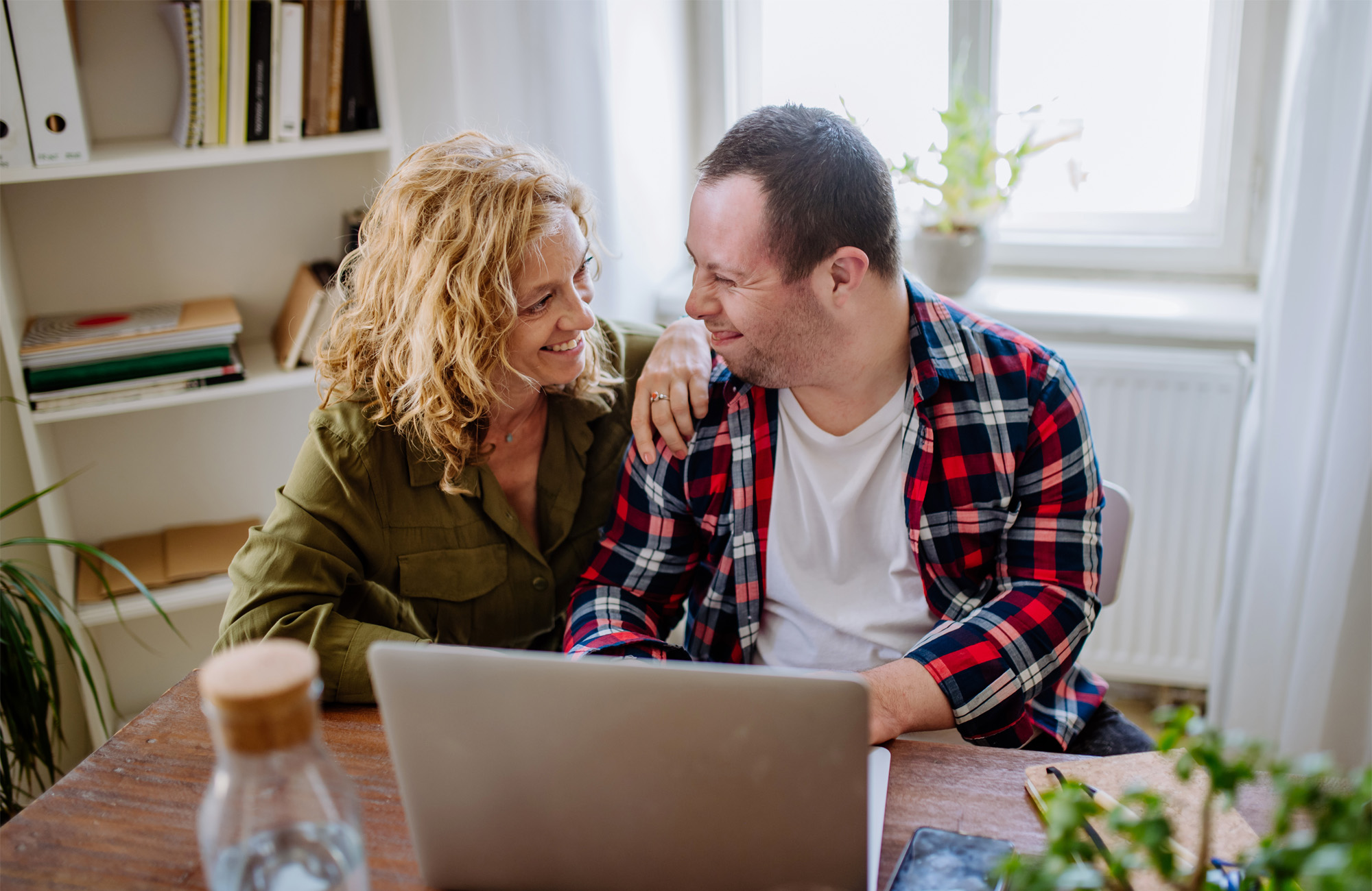 Two people sitting at a table with a computer in front of them.
