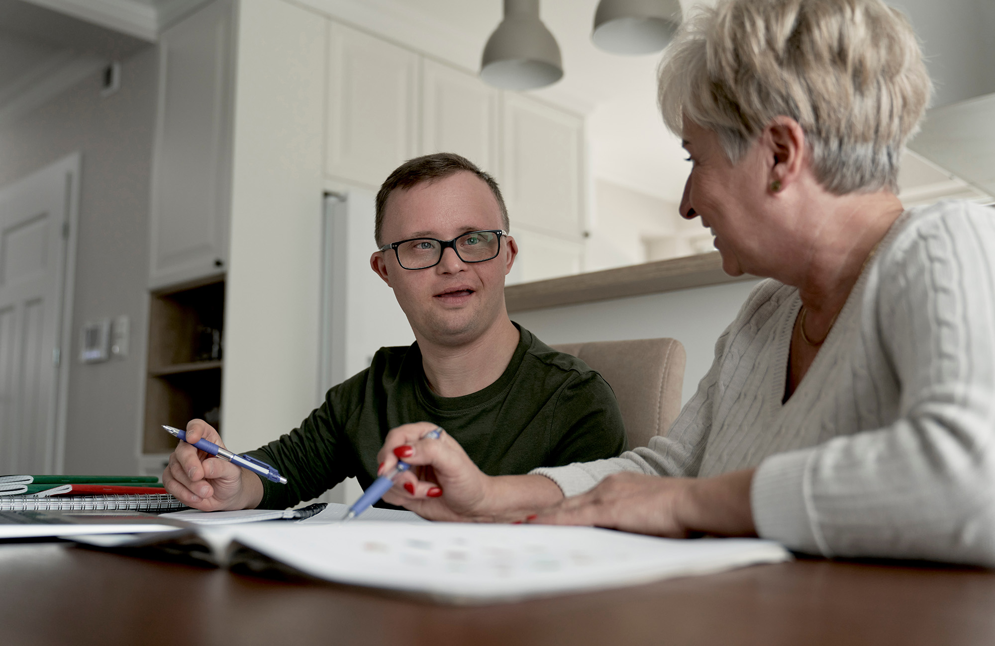 Two individuals sitting at a table looking at one another with papers in front of them.