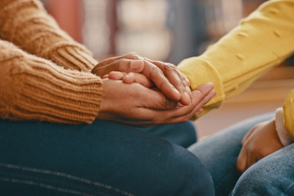 Two people holding hands to share support