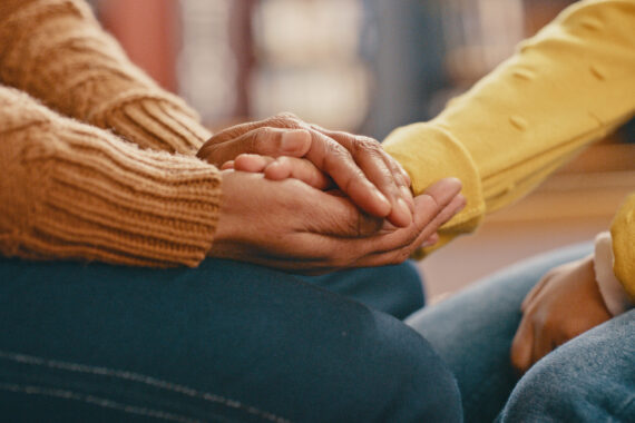 Two people holding hands to share support