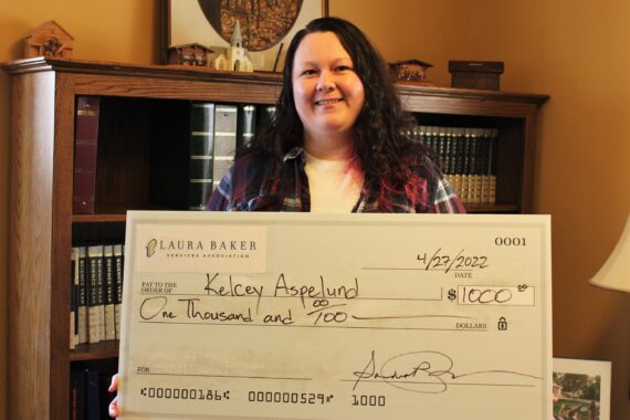 LBSA staff member Kelcey Aspelund holding scholarship check