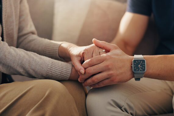 Person gently holding another person’s hands.