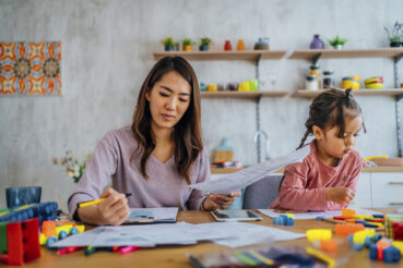 Mother goes through finances with daughter playing nearby