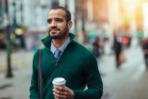 man holding coffee wearing green sweater