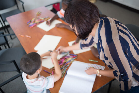 Student gets help coloring from teacher