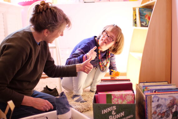 Two people organizing belongings holding their thumbs up