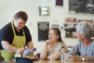 Person with IDD is serving patrons at cafe