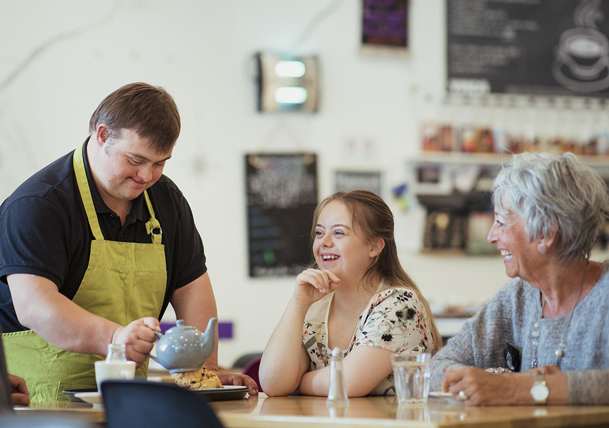 Person with IDD is serving patrons at cafe